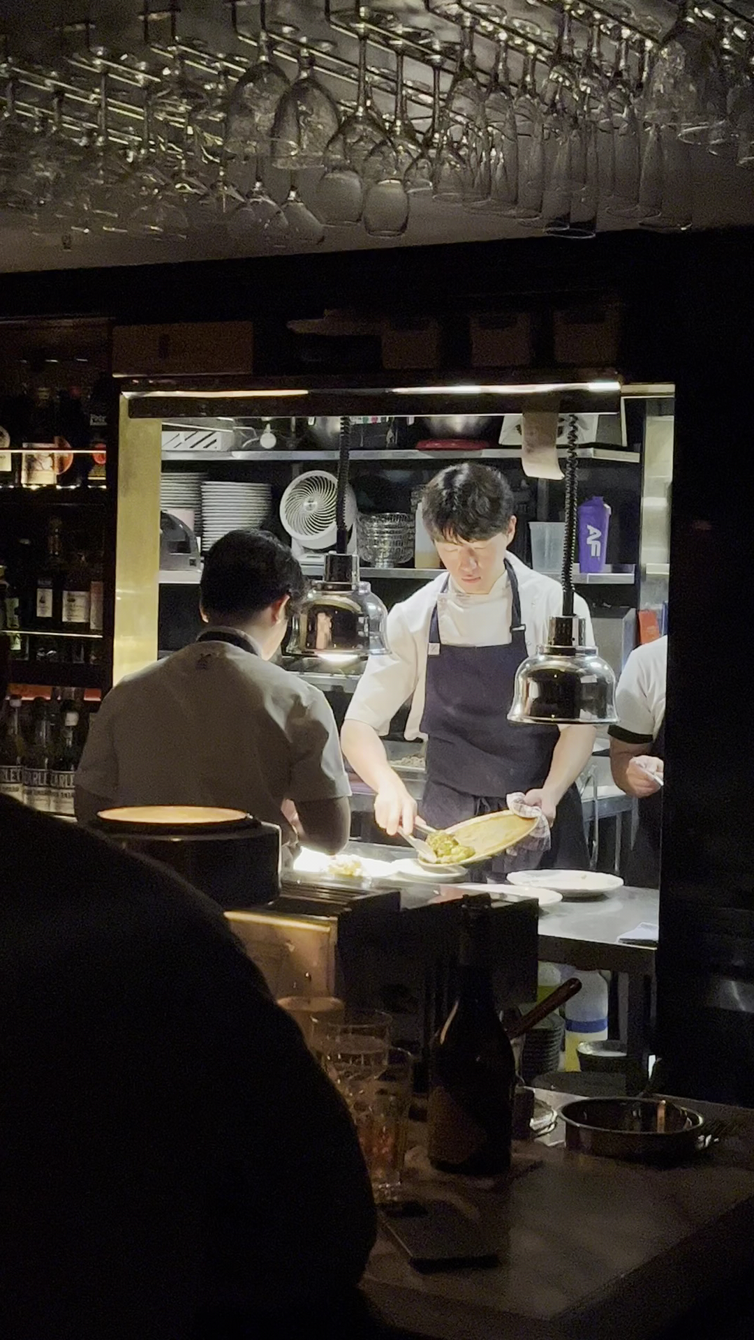 The open kitchen framed by glassware and low light